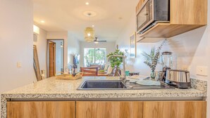 A modern kitchen with granite countertops, wooden cabinets, a built-in microwave, and a blender.
