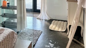 Een moderne badkamer met een douchecabine van glas, een wastafel met toiletartikelen en uitzicht op de omgeving.
