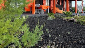 Een modern gebouw met een stenen gevel en rode accenten, met terras en een tuin.