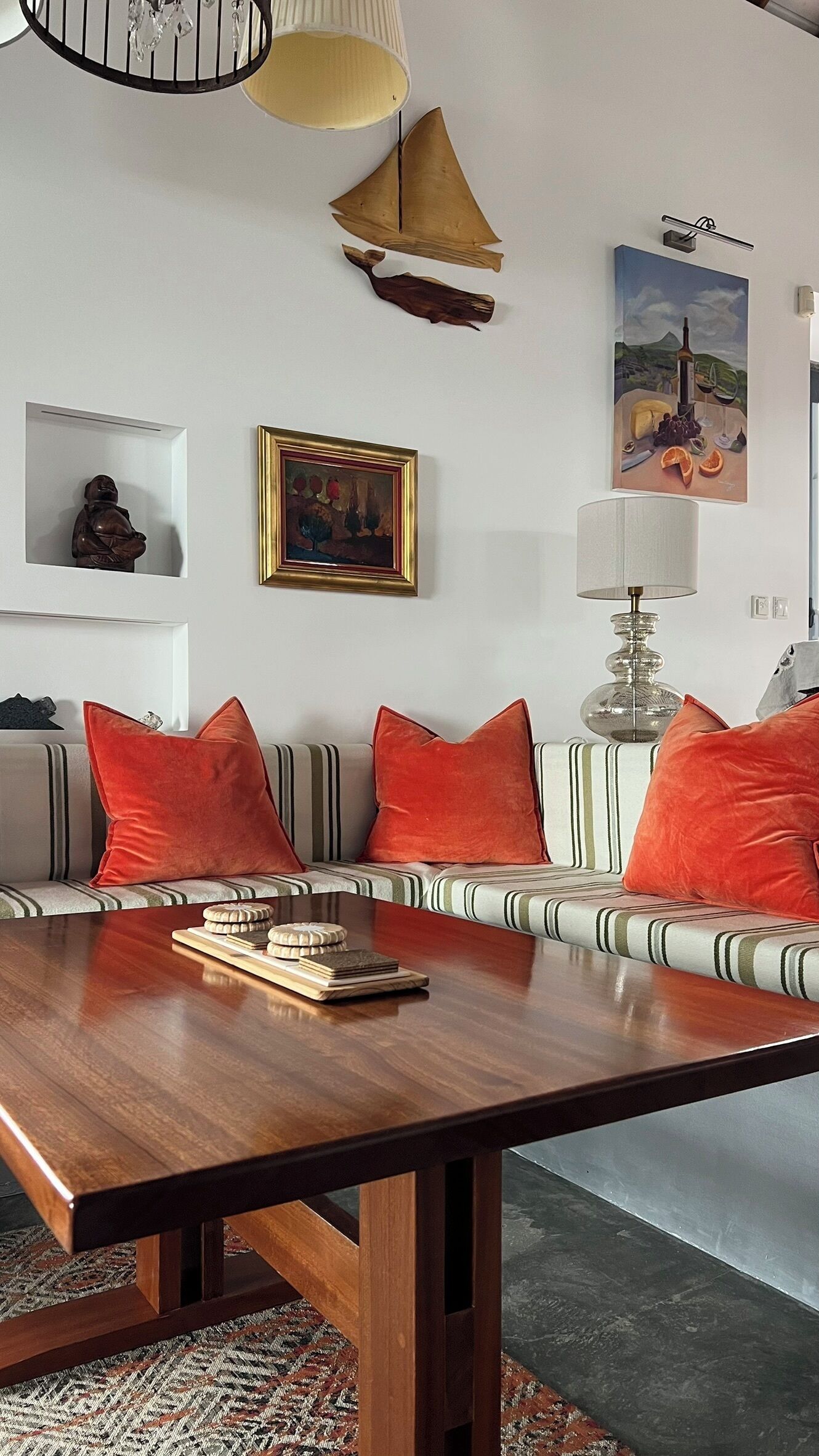 Ein modernes Wohnzimmer mit Couchtisch aus Holz, gestreifter Couch und roten Kissen.