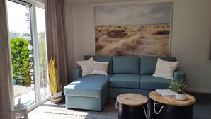 A modern living room with a sectional sofa, a large landscape painting, and two round wooden tables.