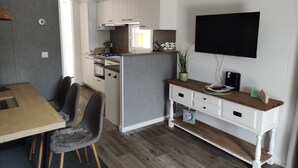 A compact kitchen with white cabinets, a built-in stove, and a dining area with a wooden table and chairs.