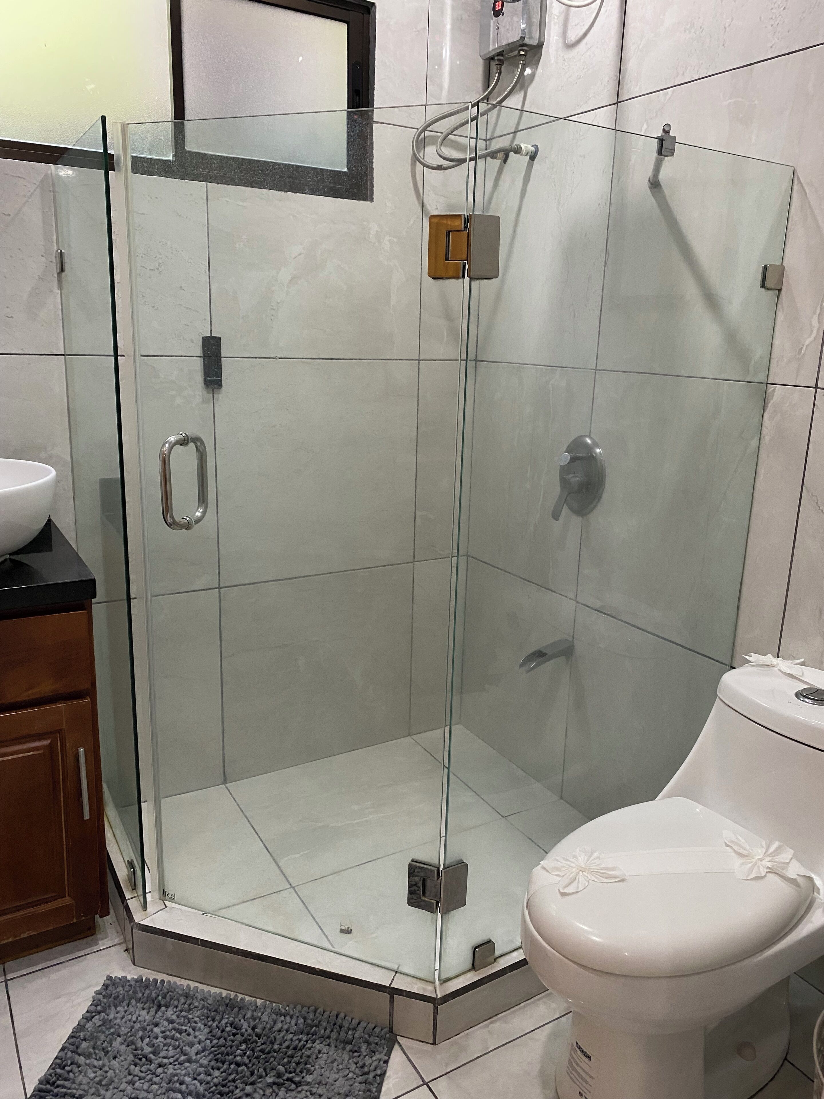 A bathroom with a glass-enclosed shower, a toilet, and a sink.