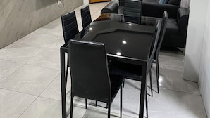 Un salón moderno con un sofá negro grande, una puerta de madera y un televisor montado en la pared.