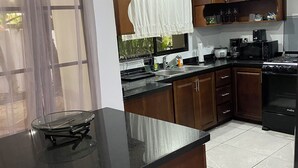 Una cocina moderna con armarios de madera, encimera negra y estufa integrada.