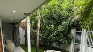 Un paseo techado con suelo de baldosas, grandes macetas y un exuberante jardín.