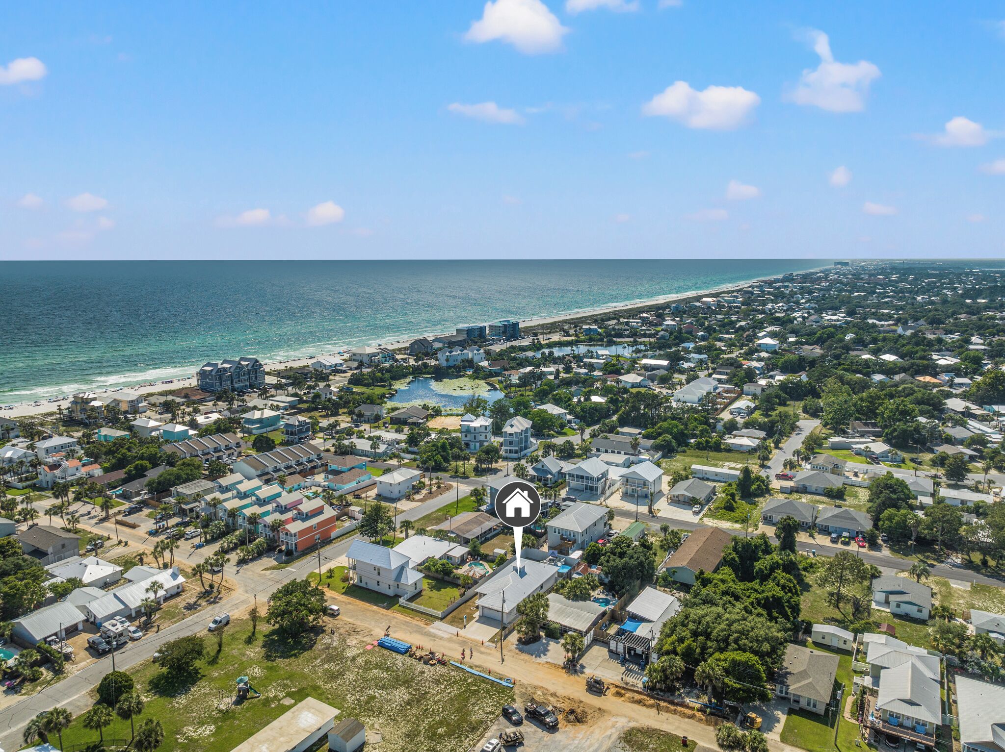 Vista aérea de una zona residencial costera con casas, una playa y cielo despejado.