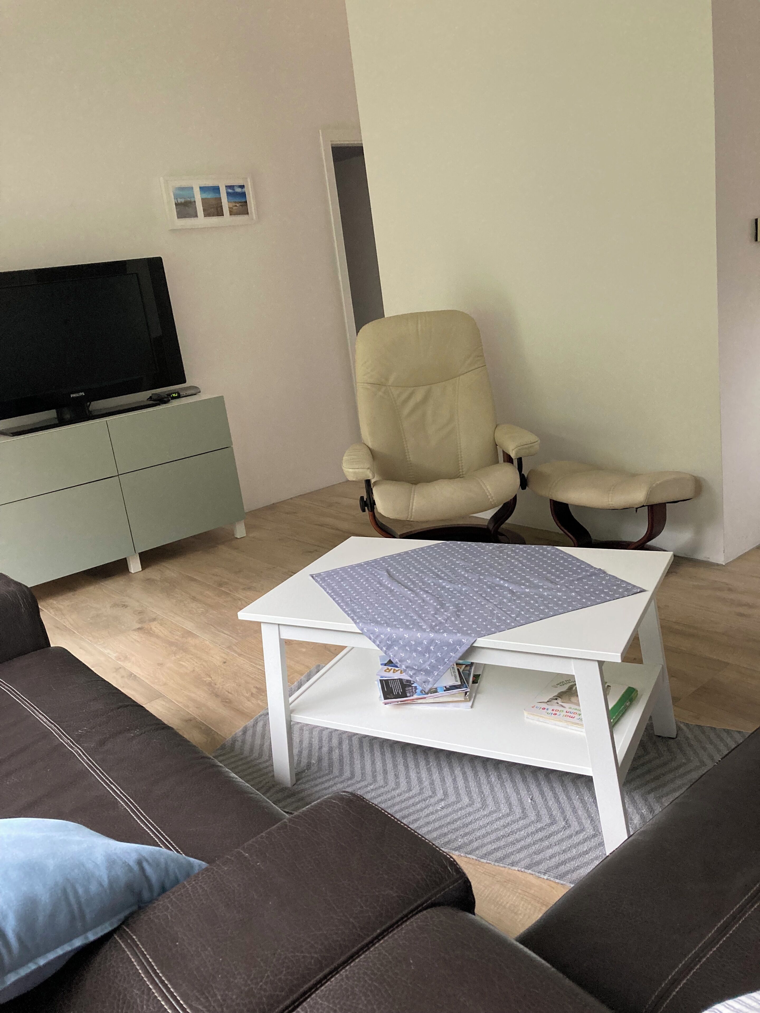 Ein Wohnzimmer mit einer Couch, einem Couchtisch, einem Fernseher und einem Sessel.