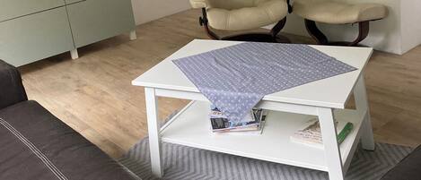 Ein Wohnzimmer mit einer Couch, einem Couchtisch, einem Fernseher und einem Sessel.
