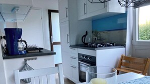 A modern kitchen with white cabinets, a stove, and a coffee machine.