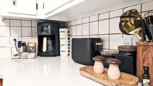Een keuken met witte kastjes, een koffiezetapparaat, een broodrooster en een decoratieve paddenstoelenaccessoire.