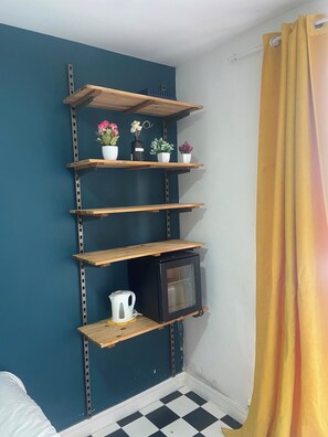 Eine Ecke mit einer türkisfarbenen Wand, einem schwarzen Schrank und einem gelben Vorhang.
