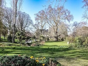 Ein Park mit einer Rasenfläche, Bäumen und einem Gebäude im Hintergrund.
