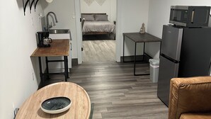 A compact living space with a kitchenette, a bed, a dining area, and a seating area.