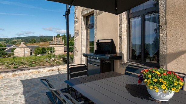An outdoor patio with a grill, a table, and chairs.