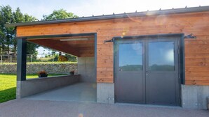 A modern building with a wooden exterior, a concrete base, and a large door.