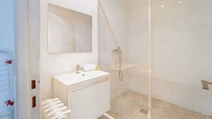 A modern bathroom with a glass shower enclosure, a white sink, and a mirror above the sink. - Au Pied de la Butte Montmartre Avec Toutes Sortes de Commerces à Moins de 5 Mins (Paris)