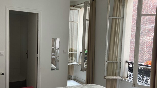Une chambre à coucher avec un lit, une porte et une fenêtre avec des rideaux.