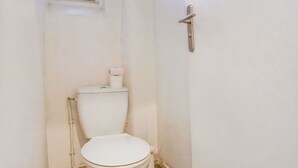 A small, white bathroom with a toilet, a window, and a door. - Au Pied de la Butte Montmartre Avec Toutes Sortes de Commerces à Moins de 5 Mins (Paris)