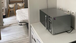 Une pièce comprenant un lit, un bureau avec un ordinateur, une chaise, une étagère et un séparateur de couleur verte.