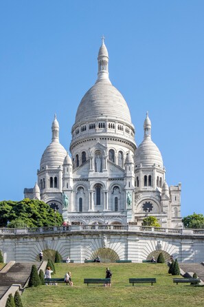 A large white domed building with multiple smaller domes and statues in front.
