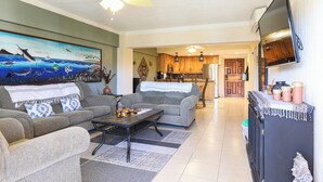 A living room with a sofa, coffee table, and a painting on the wall. - A-205 Enjoy Your Vacation In This Fabulous Remodeled Condominium! (Cabo San Lucas)