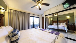 A hotel room with a large bed, a ceiling fan, a television, and a sliding door leading to a balcony. - A-205 Enjoy Your Vacation In This Fabulous Remodeled Condominium! (Cabo San Lucas)