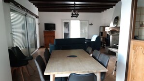 Un coin repas avec une table en bois et des chaises noires, un canapé bleu et une cheminée en pierre.