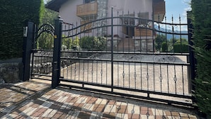 A gated entrance with a paved driveway leading to a building with a stone facade and a balcony. - Splendido Appartamento per il tuo Relax (Trentino-Alto Adige)