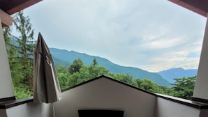 A small balcony with a bed, a chair, and a view of mountains. - Splendido Appartamento per il tuo Relax (Trentino-Alto Adige)