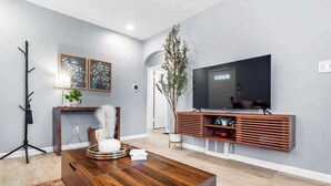 Una sala moderna con una mesa de centro de madera, un televisor de pantalla plana y una planta.