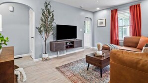 Una sala de estar moderna con un televisor de pantalla plana, un sofá, una mesa de centro y una planta decorativa.