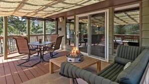 Eine überdachte Terrasse im Freien mit Feuerstelle, Sitzgelegenheiten und Blick auf die umliegende Landschaft.