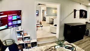 A living room with a flat-screen TV, a coffee table with a game, and a TV stand with a cabinet.