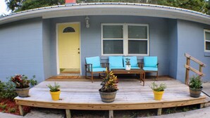 A house with a porch, a yellow door, and a window with shutters.