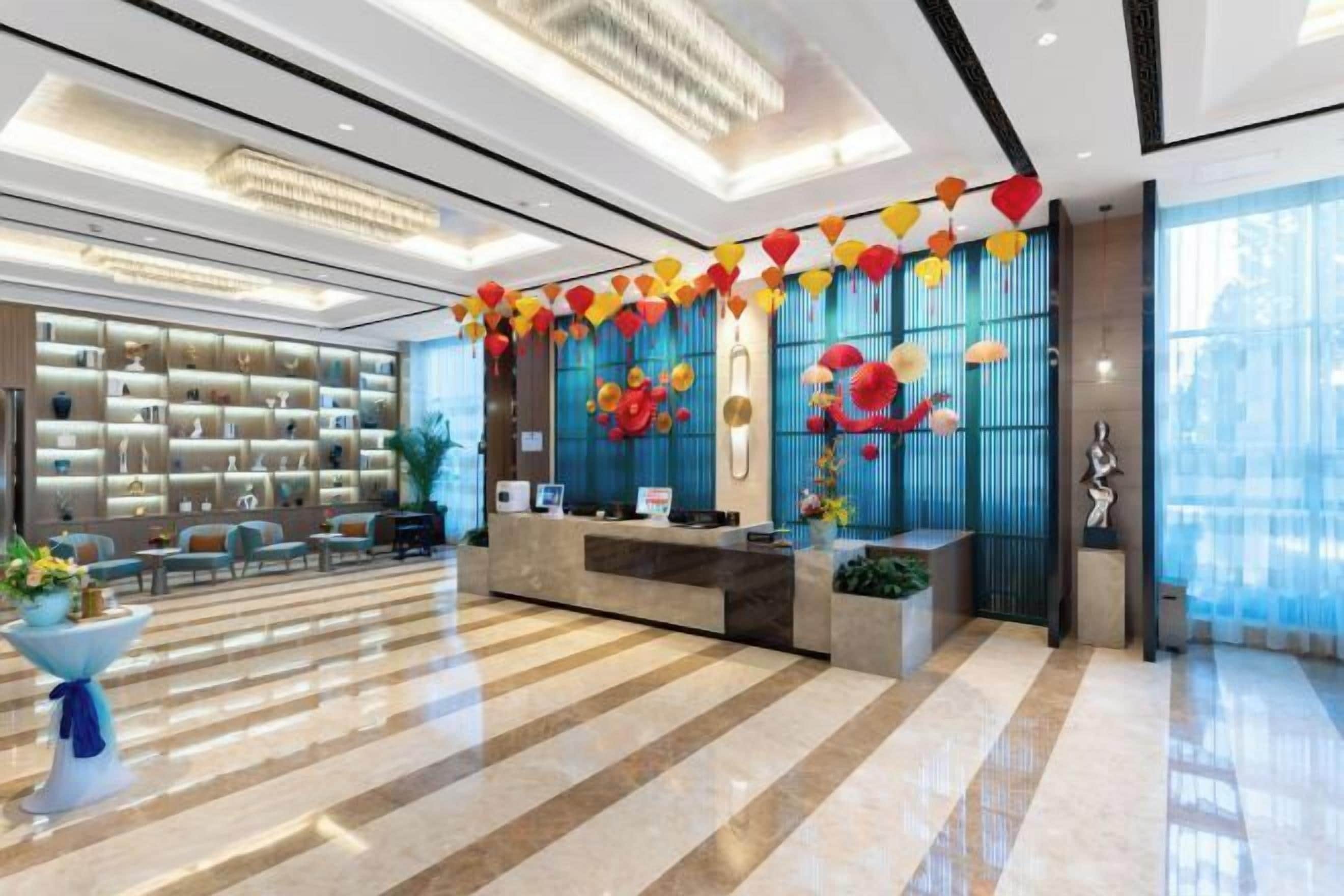 Un moderno vestíbulo de hotel con mostrador de recepción, zona de estar y una amplia estantería.