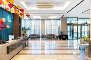 A hotel lobby with a reception desk, seating area, and large windows. - Nishi Hotel (Jinan)