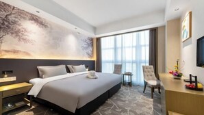 Ein modernes Hotelzimmer mit einem großen Bett, einem Schreibtisch, einem Stuhl und einem großen Fenster.