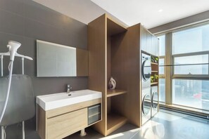 A modern bathroom with a large mirror, a white sink, a shower, and a view of the city through large windows. - Nishi Hotel (Jinan)
