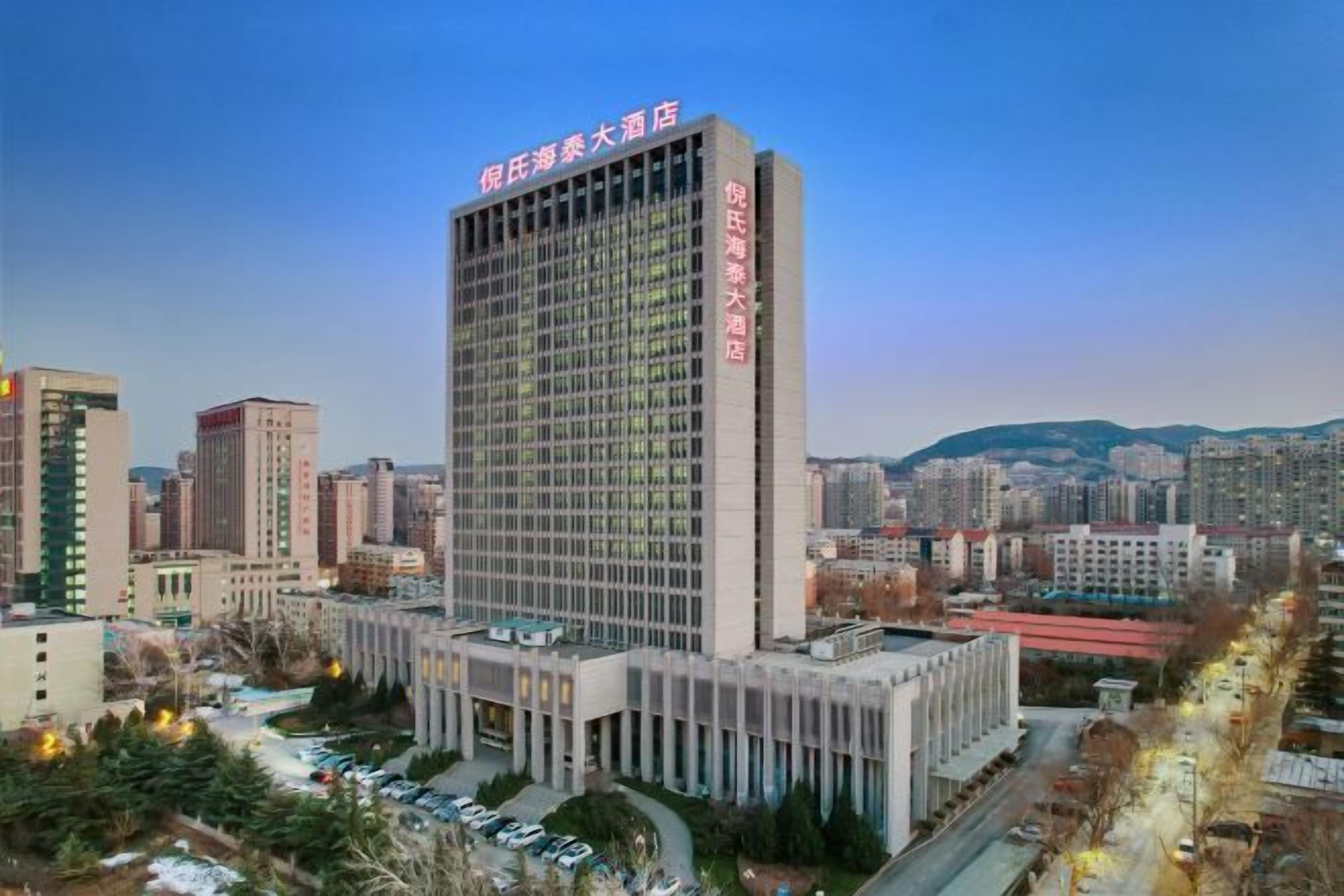 A high-rise hotel with a prominent sign, surrounded by other buildings and a clear sky.
