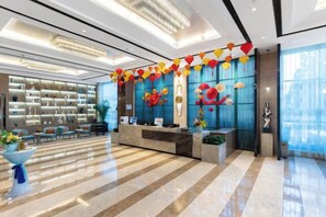 A hotel lobby with a reception desk, seating area, and a large window. - Nishi Hotel (Jinan)
