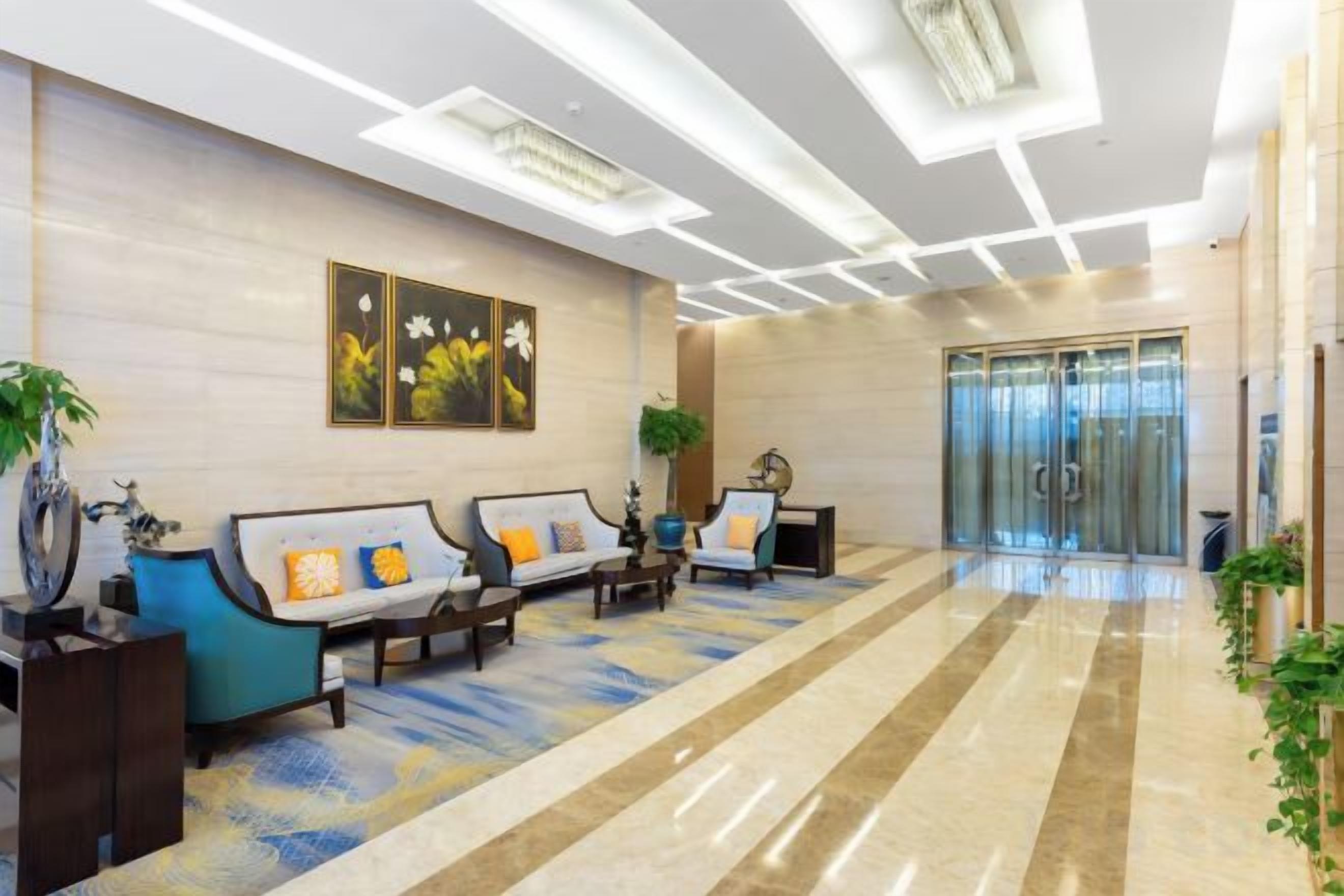 Un vestíbulo de hotel con mostrador de recepción, zona de estar y un amplio ventanal.