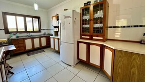 Une cuisine dotée de meubles de rangement en bois, d’un réfrigérateur et d’une fenêtre laissant entrer la lumière naturelle.