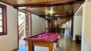 Une table de billard dans une pièce dont le sol est en bois et dont le plafond est incliné.