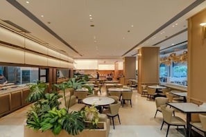 A modern interior with multiple seating areas, including round tables and chairs, and a display of plants. - Shaoxing Shangyu Radisson Wanjin Hotel (Shaoxing)
