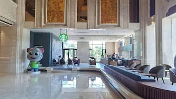 Un vestíbulo con mostrador de recepción, una estatua grande y un letrero de Starbucks.