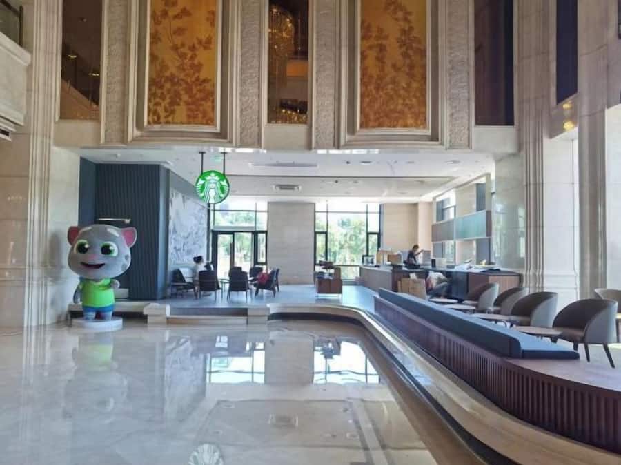 Eine Lobby mit einer Rezeption, einer großen Statue und einem Starbucks-Schild.