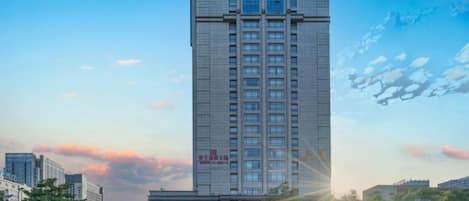 A tall hotel building with a clear sky and sunlight.
