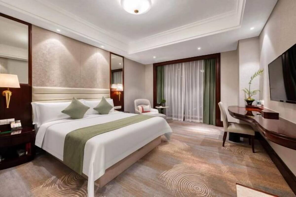A hotel room with a large bed, a desk, and a chair.