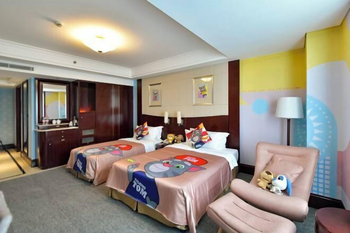 A hotel room with two beds, a desk, and a chair.